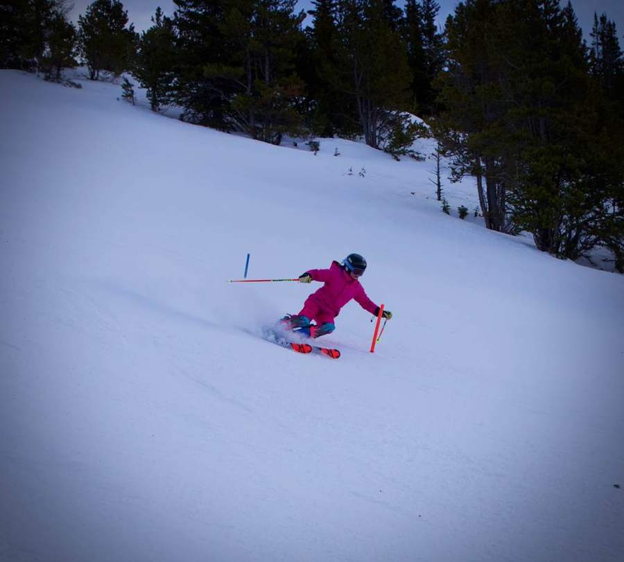 Young skier in pink carving a turn on a groomed run